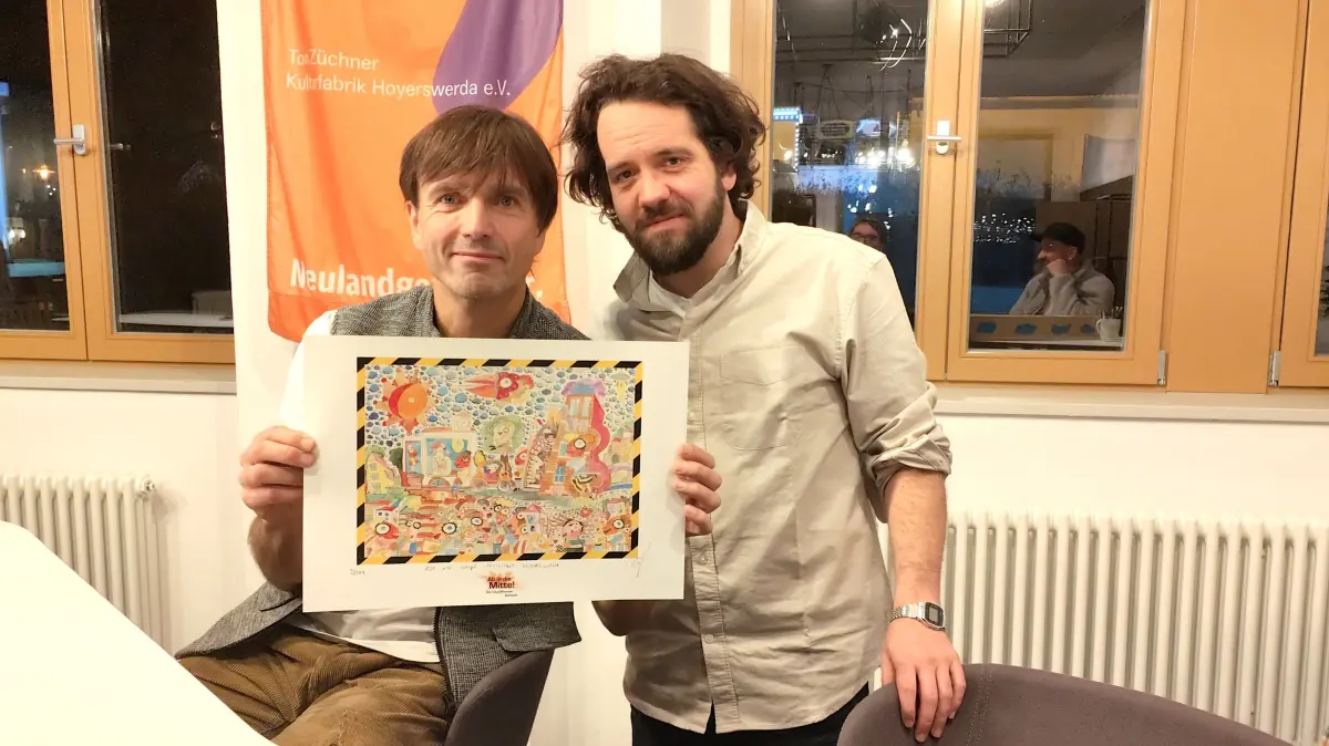 Lienig (l.) und Robert Böhme von der Stadtverwaltung präsentieren einen Druck von Fischer Art. jeder Mitwirkende am Tanzspektakel wird ein Exemplar erhalten.