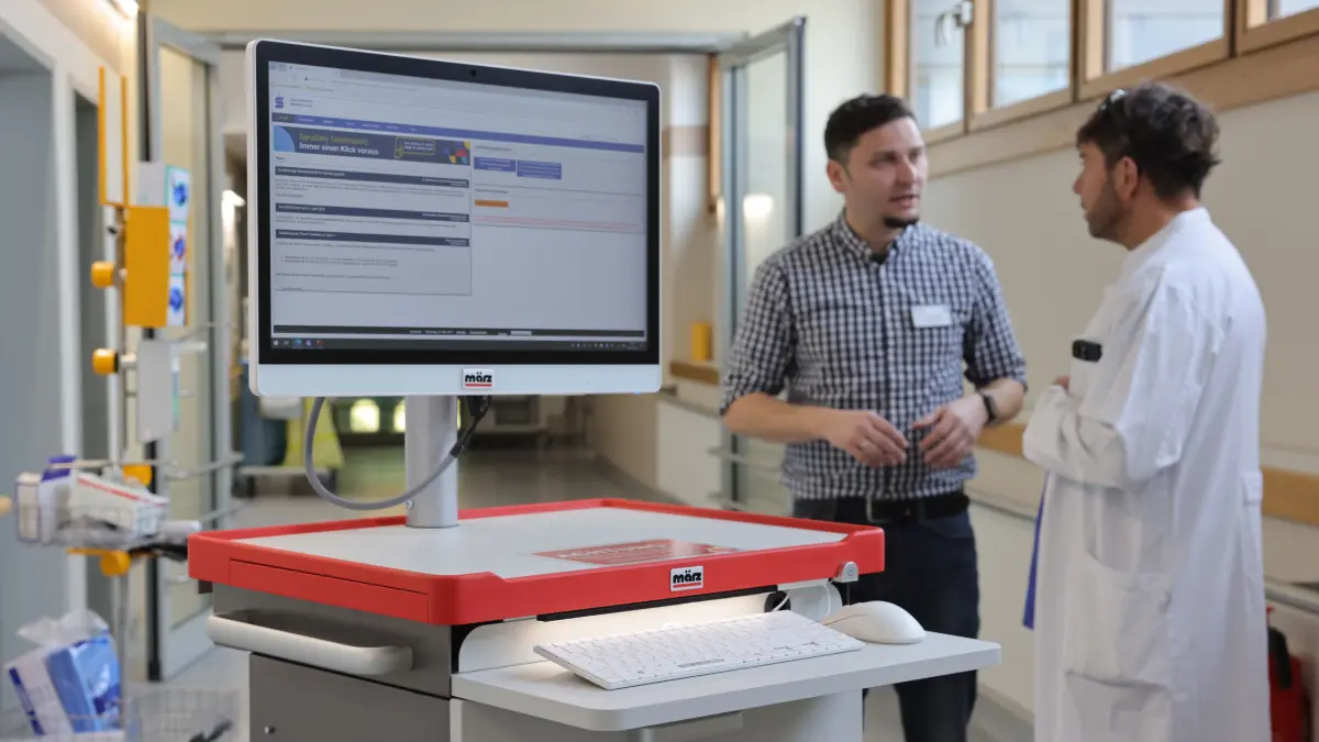 André Lehnick (l.) im Gespräch mit dem Chefkardiologen Prof. Dr. Guido Matschuck. Im Vordergrund: einer der digitalen Visitenwagen, die zum Alltag auf Station gehören.