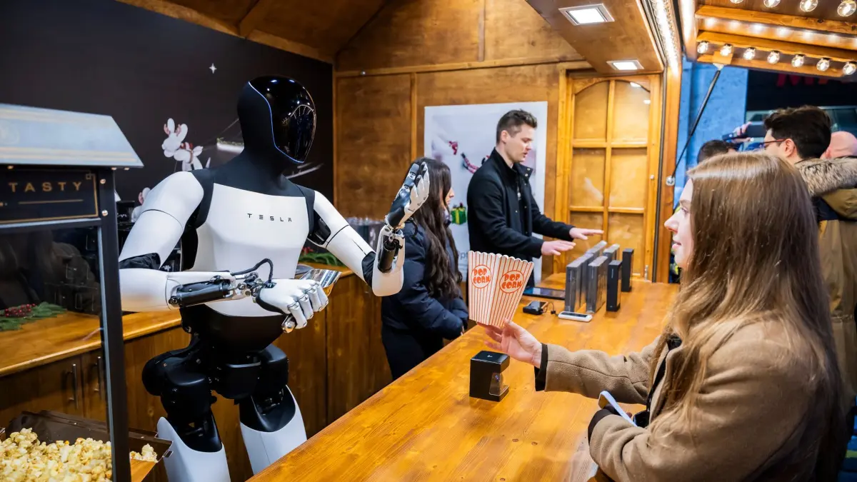 Vorstellung des humanoiden Tesla-Roboters „Optimus“: 20.12.2025, Berlin: Der humanoide Roboter «Optimus» von Tesla verteilt bei seiner Vorstellung in der Mall of Berlin Popcorn an Lisa (r). Foto: Christoph Soeder/dpa +++ dpa-Bildfunk +++