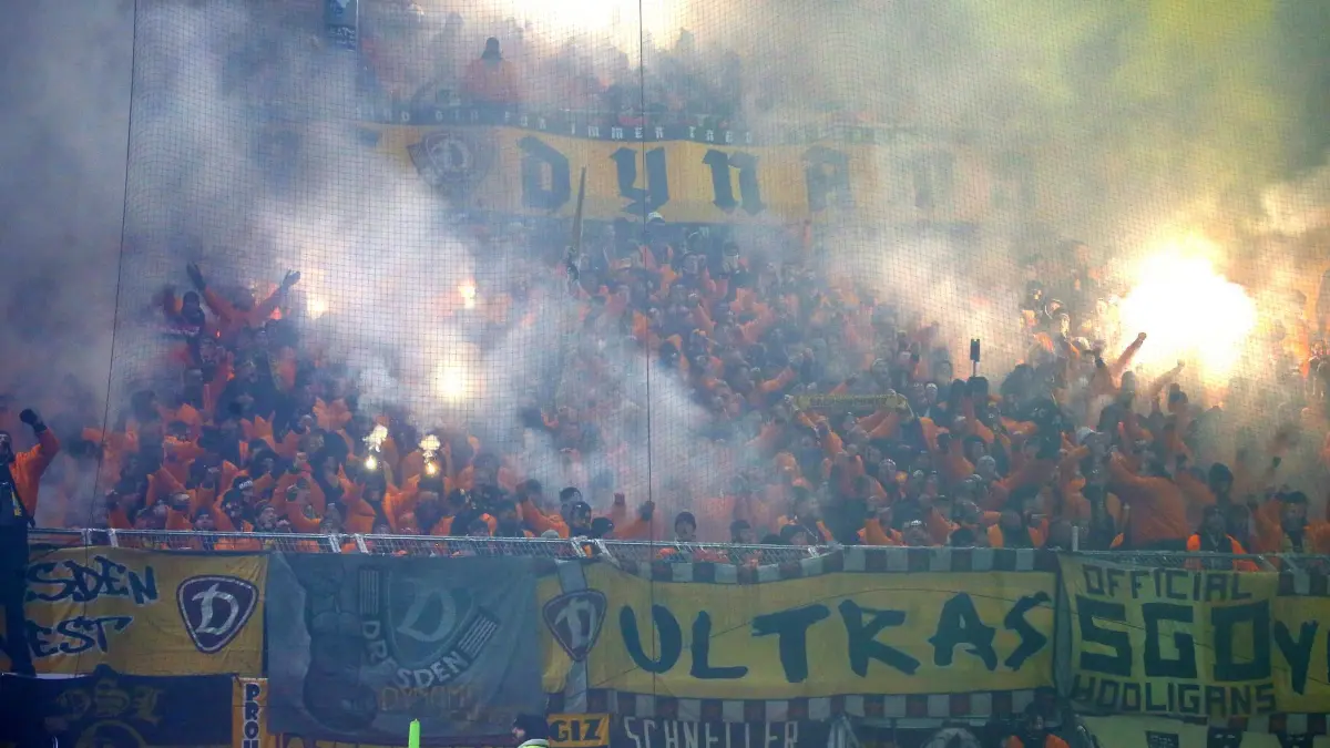 Holstein Kiel - Dynamo Dresden: 20.12.2025, Schleswig-Holstein, Kiel: Fußball: 2. Bundesliga, Holstein Kiel - Dynamo Dresden, 17. Spieltag, Holstein-Stadion. Fans von Dynamo Dresden brennen Pyrotchenik ab und werfen Feuerwerkskörper auf den Rasen Foto: Michael Hundt/dpa - WICHTIGER HINWEIS: Gemäß den Vorgaben der DFL Deutsche Fußball Liga bzw. des DFB Deutscher Fußball-Bund ist es untersagt, in dem Stadion und/oder vom Spiel angefertigte Fotoaufnahmen in Form von Sequenzbildern und/oder videoähnlichen Fotostrecken zu verwerten bzw. verwerten zu lassen. +++ dpa-Bildfunk +++