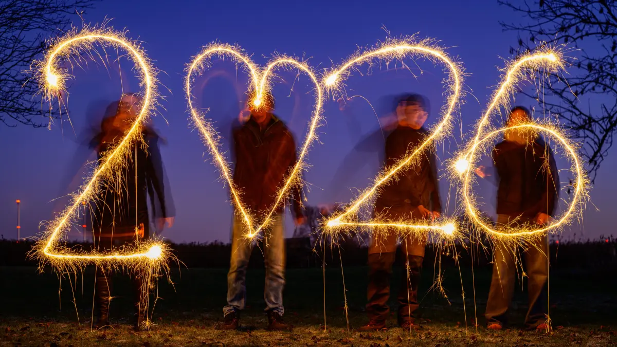 Vier Personen schreiben mit Wunderkerzen die Jahreszahl 2026 vor dem Abendhimmel (gestellte Aufnahme mit Langzeitbelichtung). +++ dpa-Bildfunk +++
