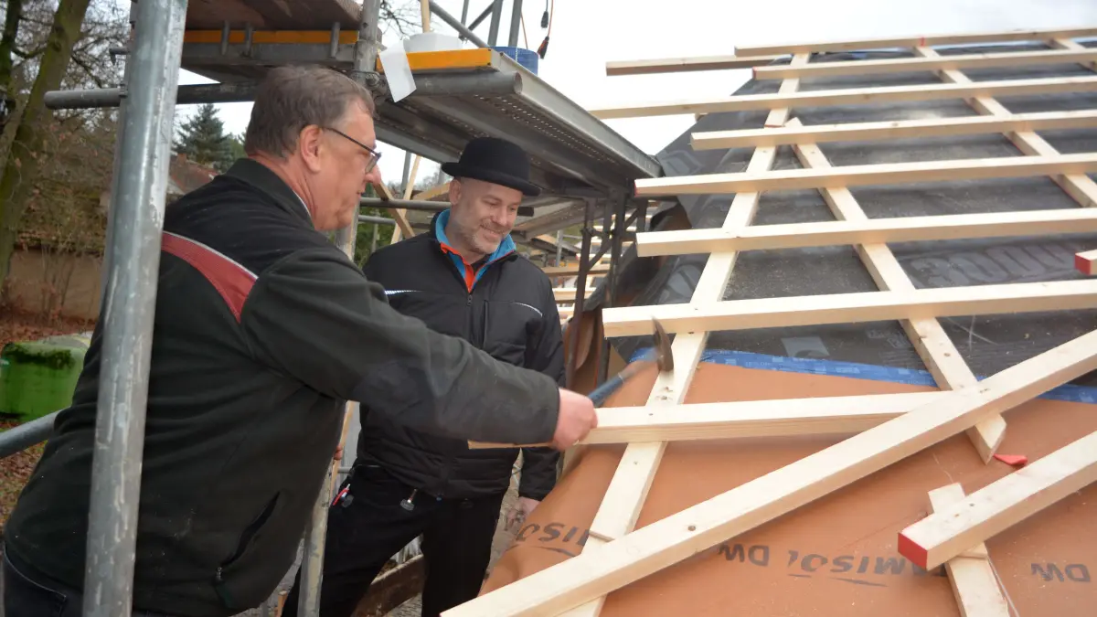 Im Beisein von Ralf Börrnert, Geschäftsführer der gleichnamigen Zimmerei & Holzbau (Dippoldiswalde) schlägt Olaf Niepraschk (l.), Leiter des Forstamtes OSL den symbolischen Nagel ins Gebälk.