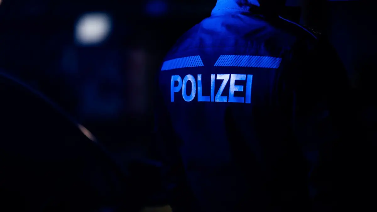 Polizei Symbolbild: ARCHIV - 18.01.2024, Sachsen, Dresden: Ein Polizist steht neben einem Polizeiauto. (zu dpa: «Polizisten in Hoyerswerda mit Feuerwerk angegriffen») Foto: Robert Michael/dpa +++ dpa-Bildfunk +++