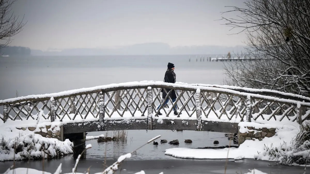 Winterwetter in Mecklenburg-Vorpommern: 06.01.2026, Mecklenburg-Vorpommern, Schwerin: Eine Frau geht über eine schneebedeckte Brücke am Schweriner See. Die Temperaturen sind unter dem Gefrierpunkt, Schnee und Eis prägen das Wetter fast im gesamten Nordosten. Foto: Philip Dulian/dpa +++ dpa-Bildfunk +++