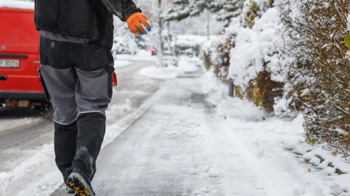 Ein Mann streut einen Gehweg: ARCHIV - Schnee und Glätte auf Gehwegen verpflichten Eigentümer und oft auch Mieter zum Räumen und Streuen. (zu dpa: «Räumen und Streuen: Was Mieter und Eigentümer tun müssen») Foto: Friso Gentsch/dpa/dpa-tmn - Honorarfrei nur für Bezieher des dpa-Themendienstes +++ dpa-Themendienst +++