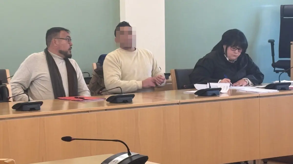 Landgericht Cottbus: Der Angeklagte (M.), hier mit seiner Verteidigerin (r.) und einem Übersetzer (l.) soll im Juli 2025 versucht haben, seinen Mitbewohner mit einem Messer zu töten. Sein Motiv gibt Rätsel auf.