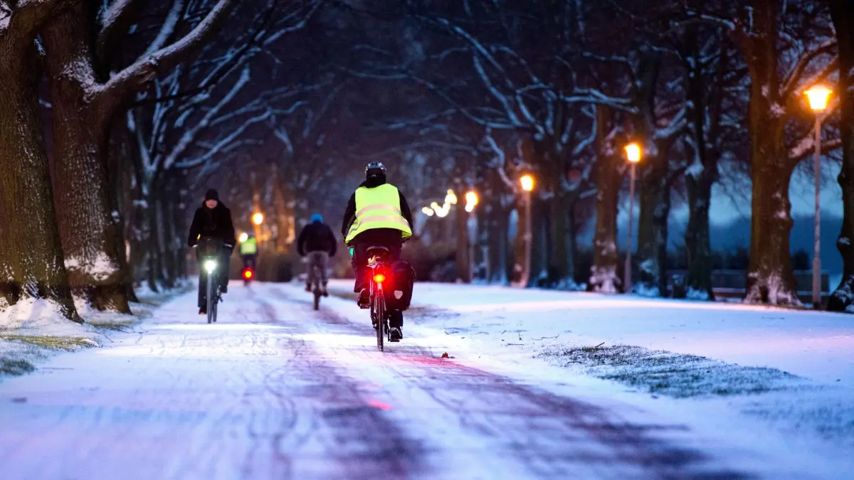 Radfahrer fahren durch eine verschneite Allee