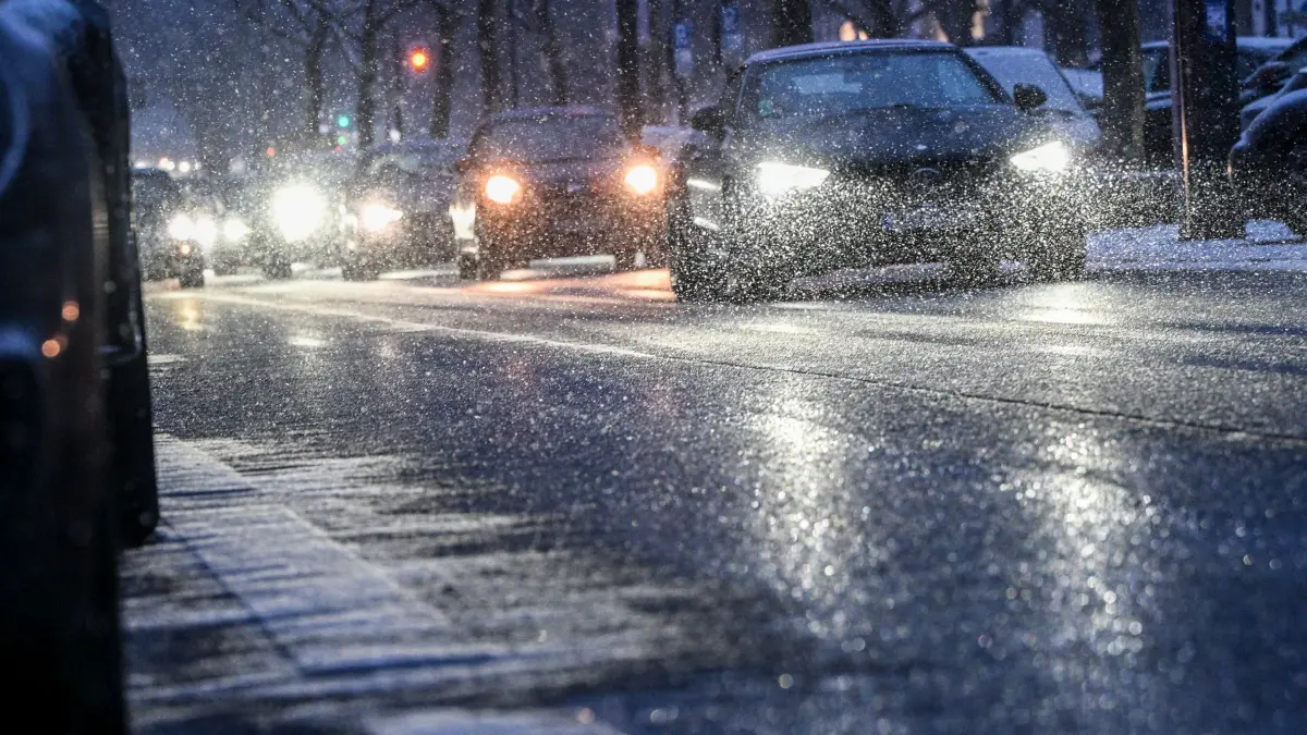 Winterwetter in Berlin: 12.01.2026, Berlin: Autos sind am frühen Abend bei einsetzendem Schneefall auf dem Kurfürstendamm unterwegs. Foto: Jens Kalaene/dpa +++ dpa-Bildfunk +++