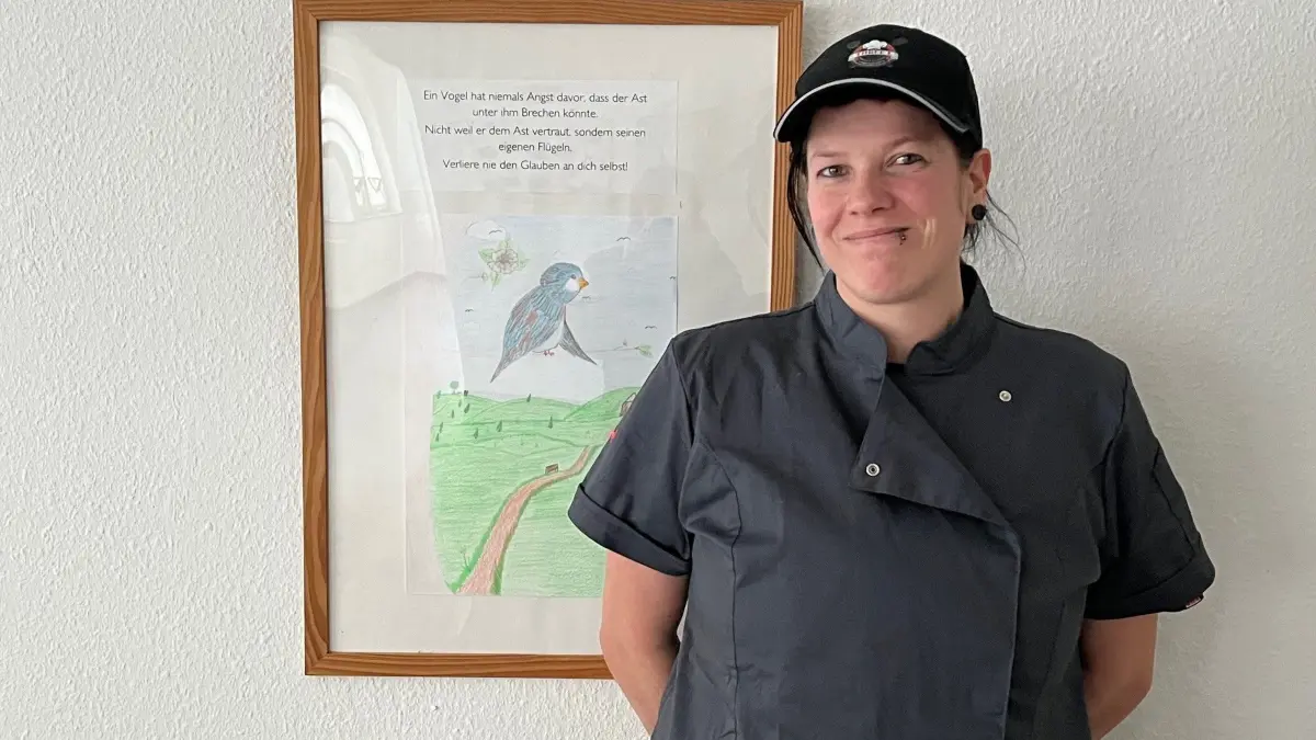 Angelina Kunath steht in dem Raum, den sie sich langfristig als kleine Kantine vorstellen kann. Der Spruch auf dem Bild neben ihr begleitet sie beim Start: „Ein Vogel hat niemals Angst davor, dass der Ast unter ihm brechen könnte … Verliere nie den Glauben an dich selbst.“