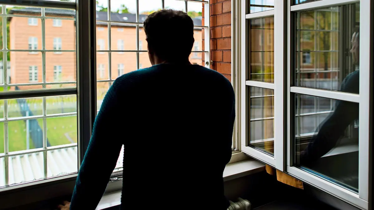 ARCHIV - 29.04.2016, Brandenburg, Eberswalde: Ein Straftäter steht vor einem vergitterten Fenster in einer Klinik für Forensische Psychiatrie (Maßregelvollzug) auf dem Gelände eines Krankenhauses. In Herne ist ein Straftäter aus dem Maßregelvollzug bei einem begleiteten Ausgang geflohen. (zu dpa: «Straftäter aus Maßregelvollzug flieht bei Ausgang») Foto: Patrick Pleul/dpa-Zentralbild/dpa +++ dpa-Bildfunk +++