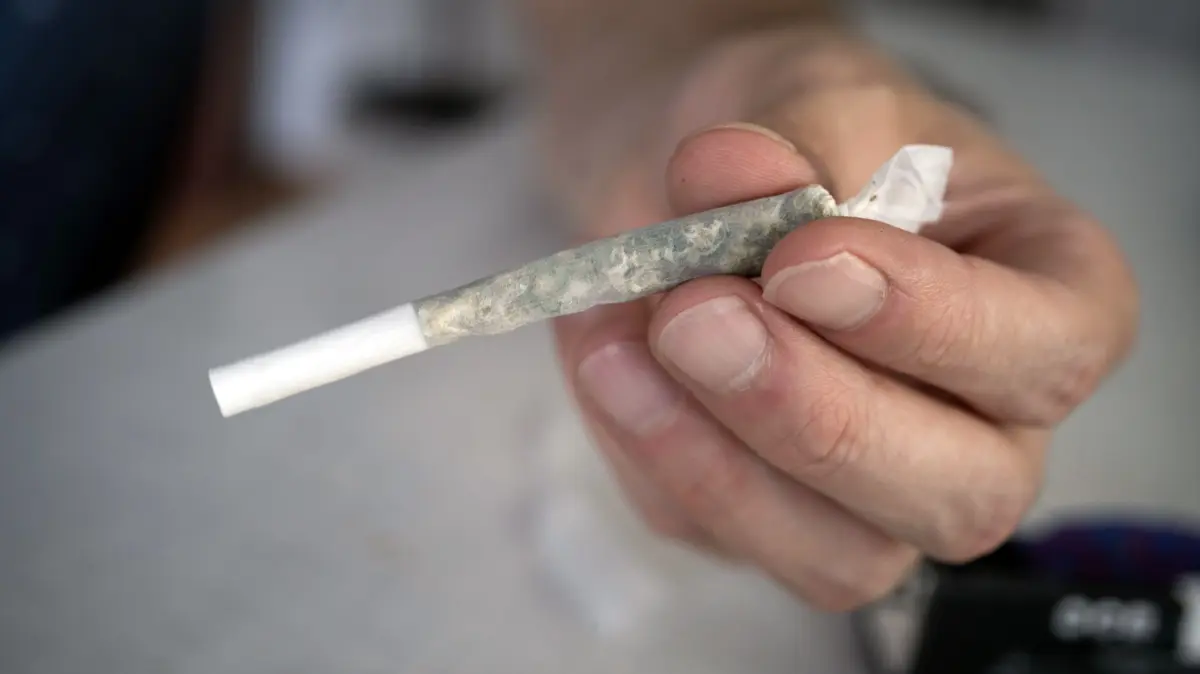 Experten fordern mehr Unterstuetzung fuer junge Drogenabhaengige: Eine Person haelt einen Cannabis - Joint in Offenbach, Hessen (Themenbild vom 21.07.2024). Experten beklagen eine unzureichende Hilfeinfrastruktur fuer jugendliche Suchtkranke. Eine Mutter eines jungen Drogenabhaengigen bringt das fast zur Verzweiflung. (Siehe epd-Bericht vom 19.01.2026) *** Local Caption *** 00510305