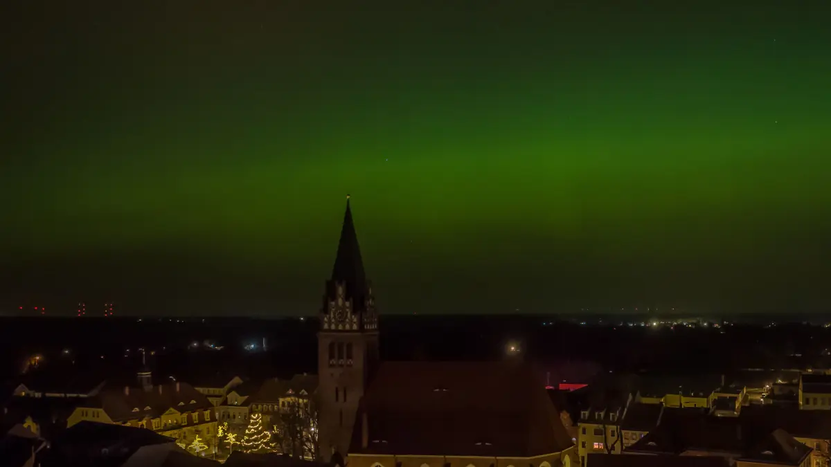 Polarlichter, ein grüner Schleier über der Innenstadt von Bad Liebenwerda mit der St.-Nikolai-Kirche.