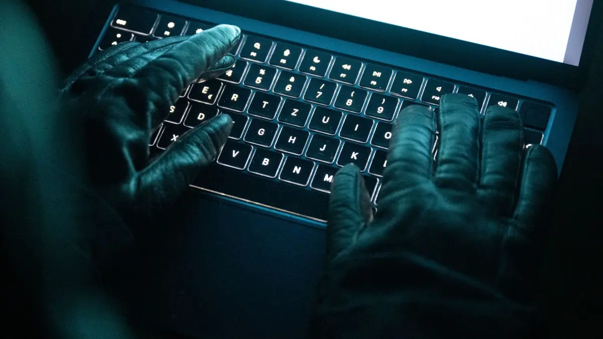Cyberkriminalität: ILLUSTRATION - 14.12.2025, NA, Berlin: Eine Person tippt mit behandschuhten Händen auf einer beleuchteten Laptop-Tastatur. (Gestellte Szene) (zu dpa: «Angriff auf Ticketportal: Schorndorf warnt vor Datenklau») Foto: Philip Dulian/dpa +++ dpa-Bildfunk +++