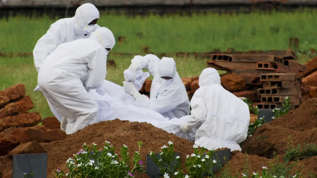 24.05.2018, Indien, Kozhikode: Rettungssanitäter in Schutzanzügen begraben ein Opfer, das aufgrund des Nipah-Virus verstarb. Beim Ausbruch des gefährlichen Nipah-Virus in Indien sind mehrere Menschen gestorben. Der Erreger kann bei Menschen Fieber, Atemwegserkrankungen und tödliche Hirnhautentzündungen verursachen. Es gibt weder eine Impfung noch eine wirkungsvolle Behandlung. Foto: K.Shijith/AP/dpa +++ dpa-Bildfunk +++