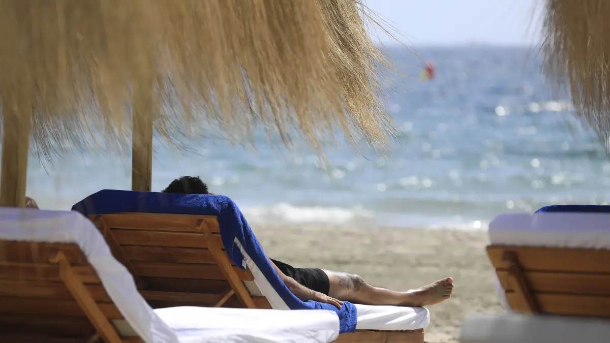 Ein Mann sonnt sich am Strand Platja d'en Bossa. +++ dpa-Bildfunk +++