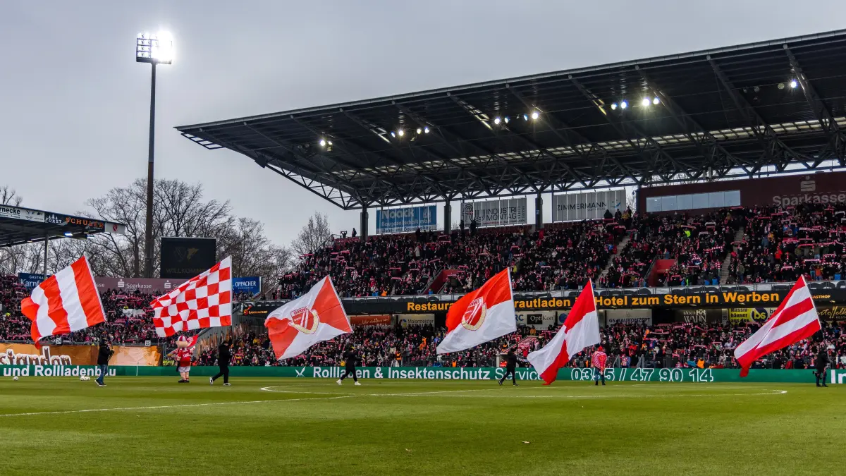 3. Liga Saison 25/26 FC Energie Cottbus vs TSG 1899 Hoffenheim II: Fußball: Dritte Liga, FC Energie Cottbus - VfB Stuttgart II, LEAG Energie Stadion: Fahnenträger laufen auf das Spielfeld. Der Verein feiert heute sein 60-jähriges Bestehen.