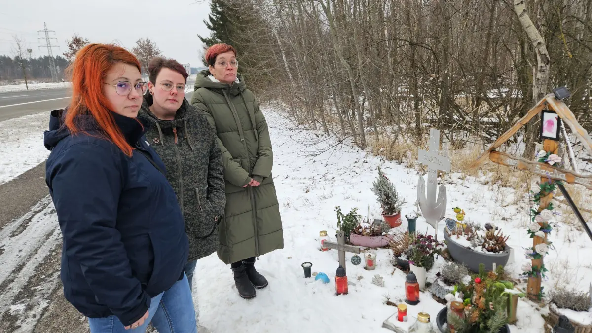 Jenny H. (li.) mit ihren Schwestern Franziska (Mitte) und Stefanie (re.) an der Unfallstelle auf der L55. Kerzen, Blumen und ein Kreuz erinnern an Sascha Helemann, der hier bei dem Frontalzusammenstoß ums Leben kam.