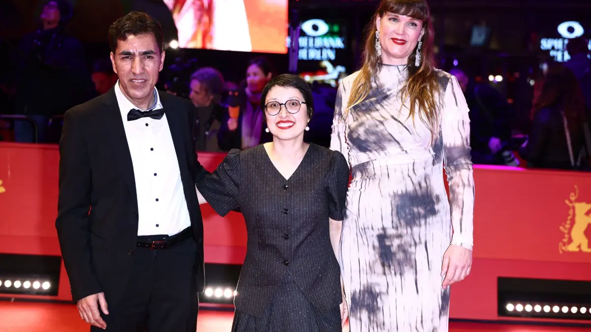 76. Berlinale - Eröffnung: 12.02.2026, Berlin: Shahrbanoo Sadat (M), Regisseurin und Hauptdarstellerin von No Good Men, und Anwar Hashimi (l), Schauspieler, und Katja Adomeit stehen am Eröffnungsabend der Berlinale auf dem Roten Teppich vor dem Berlinale Palast, wo der Film «No Good Men» Premiere feiert. Die 76. Internationalen Filmfestspiele Berlin finden vom 12. bis 22. Februar 2026 statt. Foto: Christoph Soeder/dpa +++ dpa-Bildfunk +++