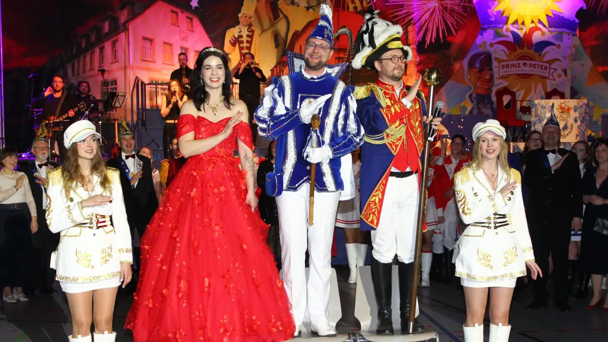 Das Dreigestirn der 320. Karnevalssaison in Wittichenau in voller Pracht. Prinz Peter (M.) mit Prinzessin Lydia und Hofmarschall Thomas sowie den Pagen Anna und Melinda beim Kappenabend. Die Prinzessin trägt ein Kleid "wie ein Sonnenaufgang".