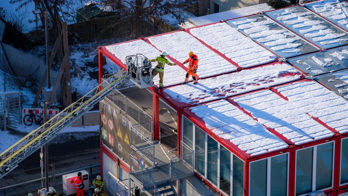 Aufgrund des simulierten Brands hat sich ein Mitarbeiter eines Nachunternehmers auf das Dach des Bürocontainers geflüchtet. Er muss von den Einsatzkräften gerettet werden.