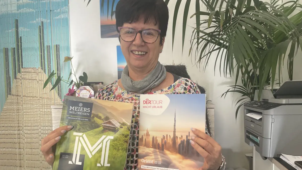 Petra Scherff, Mitarbeiterin im Reisebüro Destino in Finsterwalde, zeigt zwei Reisekataloge für den Orient beziehungsweise für Asien.