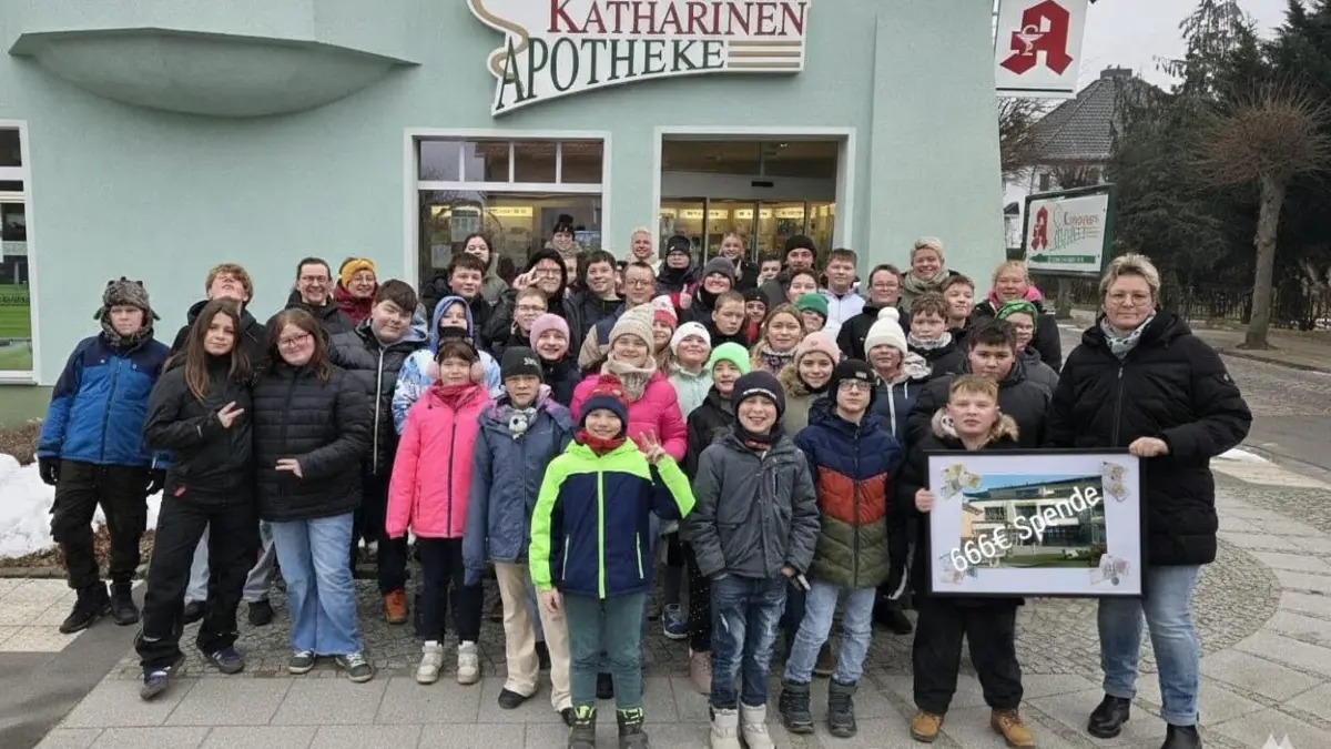Die Schülerinnen und Schüler der Ganztagsschule freuen sich über die Spende vor der Katharinen‑Apotheke – gemeinsam mit Lehrerin Anja Müller.