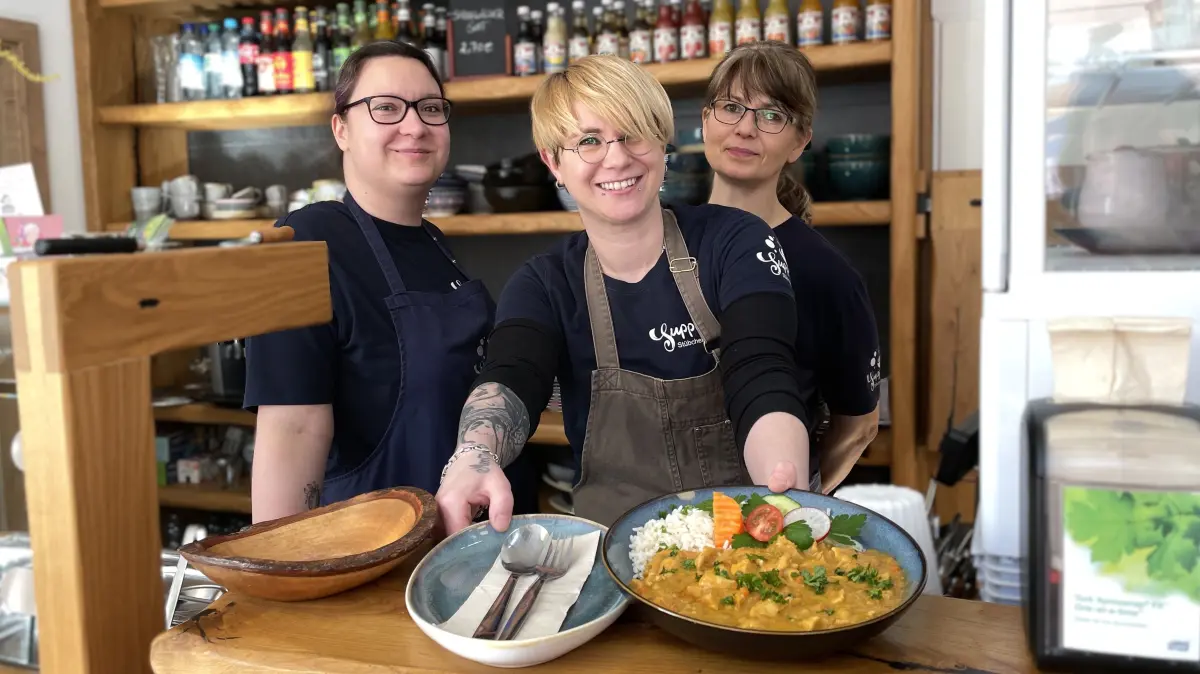 Die Mitarbeiterinnen des Suppenstübchens in Cottbus halten am 6.3.2026 einen Teller Hähnchencurry in die Kamera. V.l.n.r.: Katrin Philo, Nancy Michelko, Ramona (will keinen Nachnamen nennen)