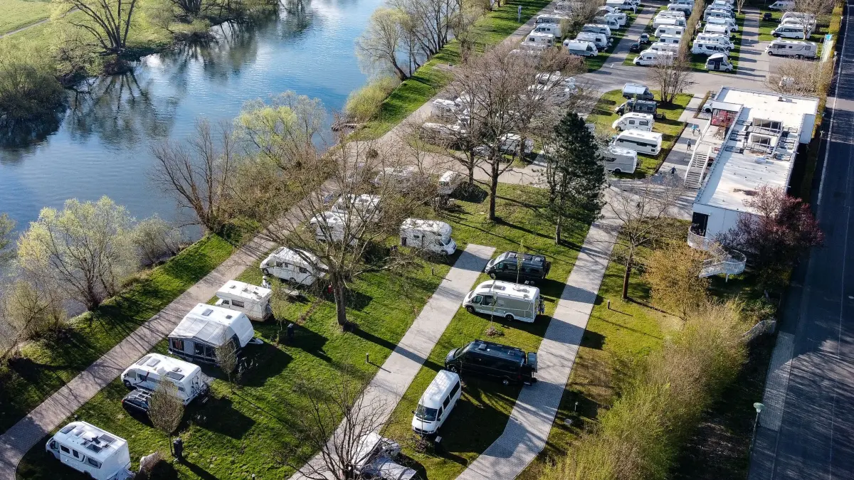 Camping in Hessen: ARCHIV - 16.04.2022, Hessen, Kassel: Wohnwagen und Wohnmobile stehen an dem Fluss Fulda auf dem Campingplatz Kassel. (Aufnahme mit einer Drohne) (zu dpa: «Camping in Hessen besonders günstig») Foto: Swen Pförtner/dpa +++ dpa-Bildfunk +++