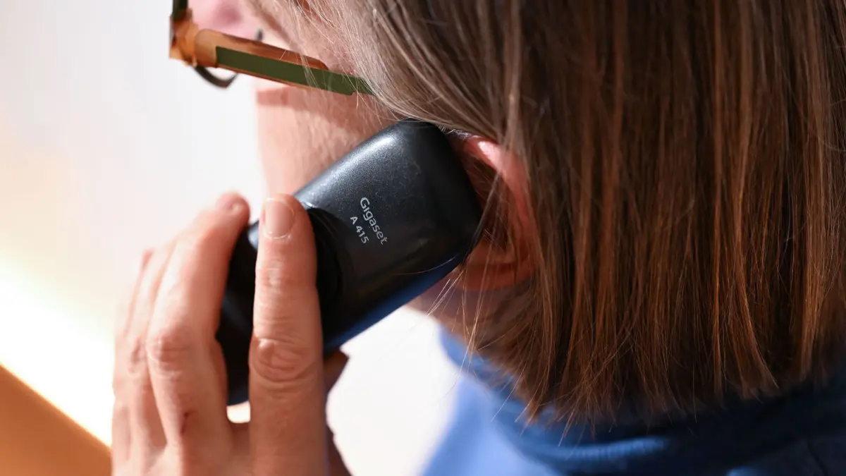 ILLUSTRATION - 07.11.2025, Baden-Württemberg, Stuttgart: Eine Frau hält ein Festnetz-Telefon ans Ohr (gestellte Szene). (zu dpa: «21-Jähriger spielt Seniorin und überführt Telefonbetrüger») Foto: Bernd Weißbrod/dpa +++ dpa-Bildfunk +++