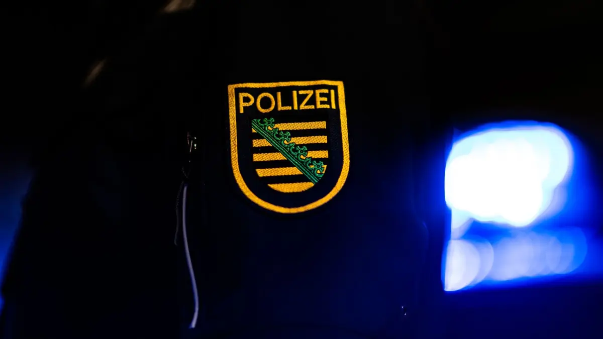 Polizei in Sachsen: ARCHIV - 18.01.2024, Sachsen, Dresden: Ein Polizist steht neben einem Polizeiauto. (zu dpa: «Polizei rettet zurückgelassene Katze aus Wohnung») Foto: Robert Michael/dpa +++ dpa-Bildfunk +++