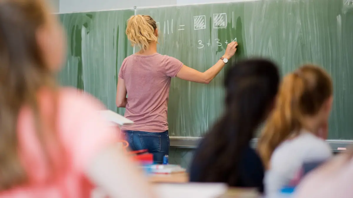Sachsen-Anhalt regelt Einstieg für Seiteneinsteiger neu: ARCHIV - 09.06.2022, Niedersachsen, Hannover: Eine junge Lehrerin schreibt im Mathematikunterricht Zahlen an eine Schultafel. (zu dpa: «Seiteneinsteiger an Schulen: Einstieg wird neu geregelt») Foto: Julian Stratenschulte/dpa +++ dpa-Bildfunk +++