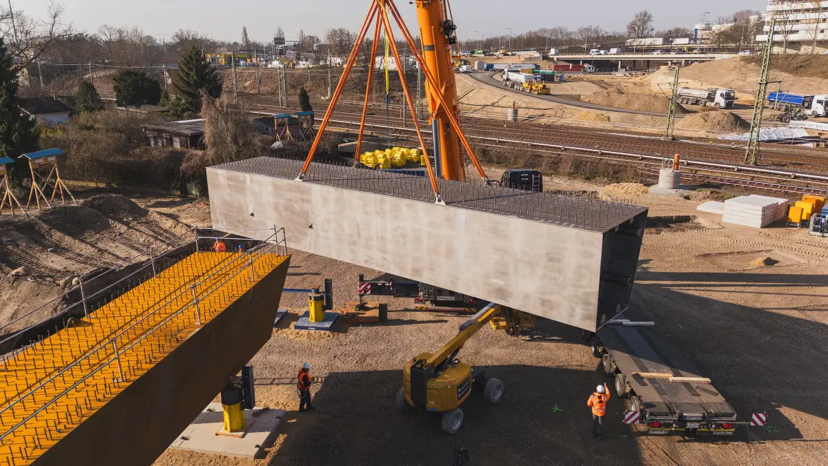 Einzelteile der neuen Ringbahnbrücke in Berlin werden von Kränen auf die Baustelle an der A100 gehieft.