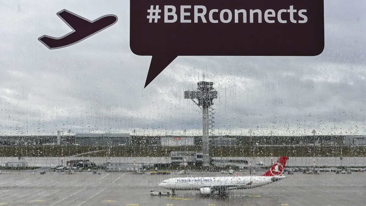 Aufkleber sind auf der Scheibe der Besucherterrasse am Flughafen BER bei Regenwetter vor einem Flugzeug zu sehen. Am 31. Oktober 2020 öffnete der Flughafen nach vielen Verzögerungen und Pannen. +++ dpa-Bildfunk +++