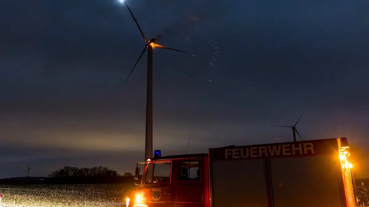 Datum: 30.03.2026 / Ort: Crostwitz
In den fruehen Morgenstunden gegen 0:45 Uhr wurden die Feuerwehr Crostwitz sowie mehrere umliegende Feuerwehren mit dem Einsatzstichwort ,,Brand 1 - brennt Windrad" auf die Ortsverbindung zwischen Crostwitz und Sibnitz alarmiert. Bereits auf der Anfahrt war ein Feuerschein aus groesserer Entfernung sichtbar. Beim Eintreffen der ersten Einsatzkraefte bestaetigte sich die Lage: Der Maschinenraum (Gondel) eines Windrades stand in voller Ausdehnung in Flammen. Aufgrund der Hoehe der Anlage und der intensiven Brandentwicklung war eine direkte Brandbekaempfung im oberen Bereich nicht moeglich. Zu diesem Zeitpunkt waren bereits mehrere brennende Truemmerteile vom Windrad herabgestuerzt und hatten am Boden zusaetzliche Brandstellen verursacht. Diese wurden durch die Einsatzkraefte umgehend lokalisiert und abgeloescht, um eine weitere Ausbreitung des Feuers zu verhindern. Die Feuerwehr sicherte die Einsatzstelle grossraeumig ab und sperrte den Gefahrenbereich weitraeumig, um sowohl Einsatzkraefte als auch die Bevoelkerung vor herabfallenden, teils gluehenden Bauteilen zu schuetzen. Parallel dazu wurde eine kontinuierliche Brandwache eingerichtet, um weitere herabfallende Teile sofort bekaempfen zu koennen. Aufgrund der besonderen Einsatzlage konzentrierten sich die Massnahmen auf die Kontrolle des Brandgeschehens sowie die Verhinderung einer Ausbreitung im Umfeld der Anlage. Der Brand im Maschinenraum selbst musste kontrolliert ausbrennen. Der Einsatz zog sich ueber mehrere Stunden hin. Nach Abschluss der aktiven Massnahmen verblieb eine Brandwache an der Einsatzstelle, um moegliche Glutnester weiterhin zu ueberwachen.