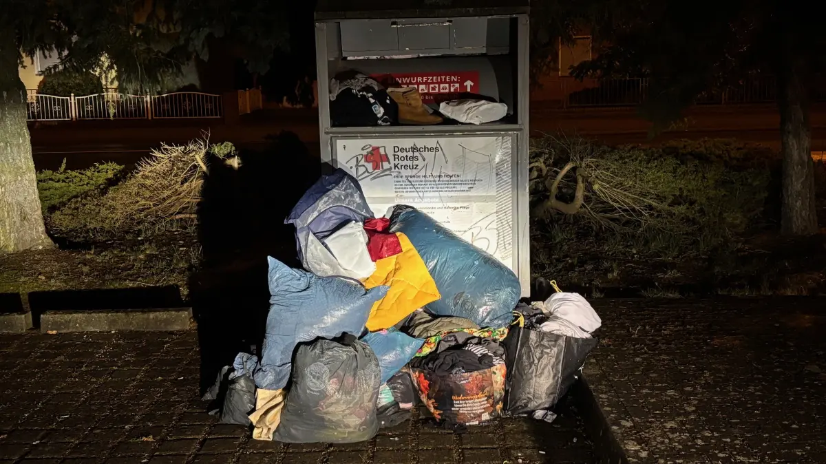 Dieser Altkleidercontainer des DRK-Kreisverbandes Lausitz steht auf der alten Schwarzheider Rollschuhbahn. Der Behälter quillt über, die Leute werfen ihre Säcke daneben.