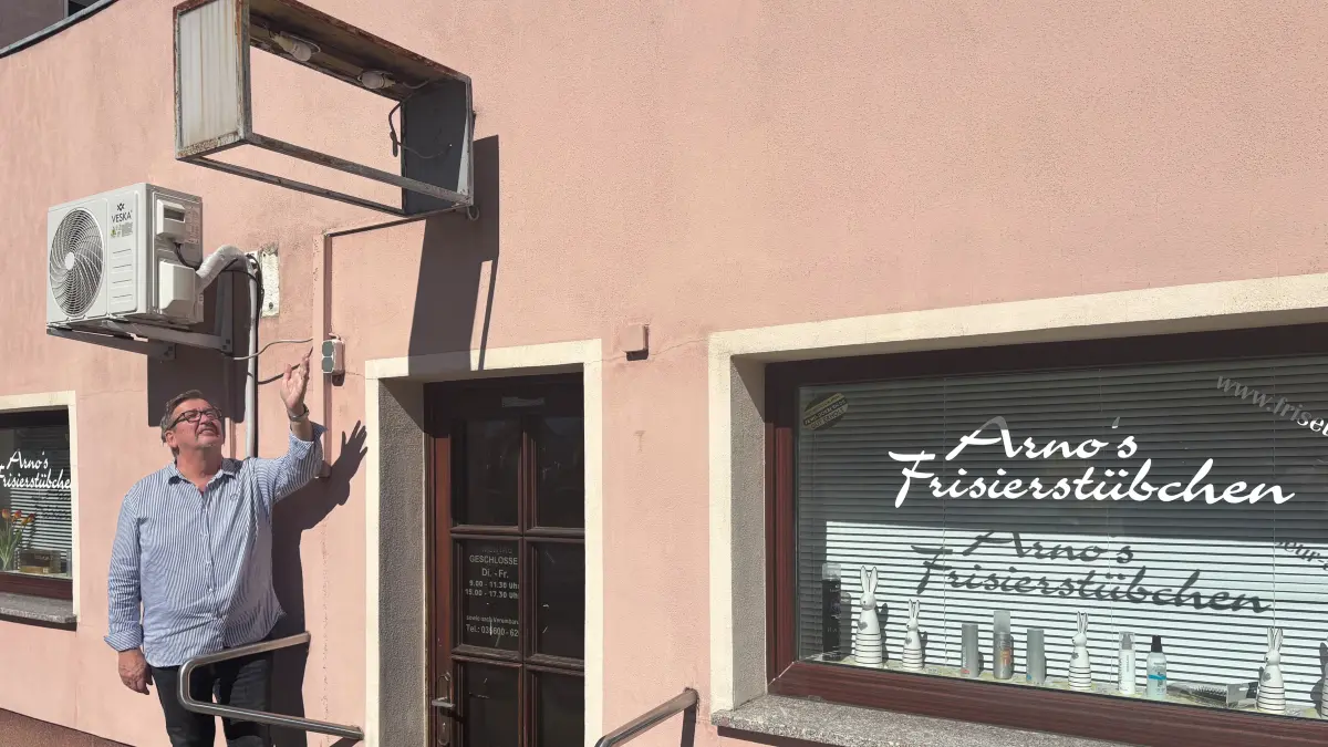 Friseurmeister Arno Asmus zeigt auf die leere Leuchtreklame über dem Eingang zu seinem Geschäft in Döbern. Der Gewerbetreibende ist offenbar Opfer eines Vandalismusvorfalls geworden.
