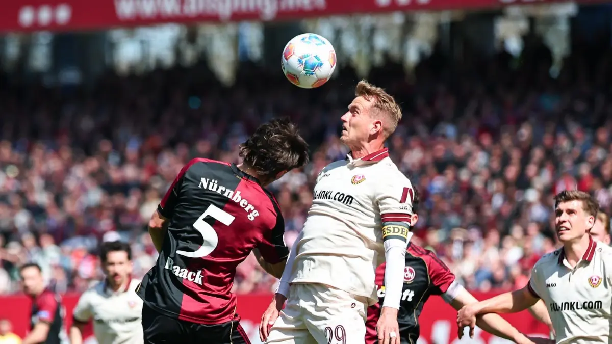 1. FC Nürnberg - Dynamo Dresden: 11.04.2026, Bayern, Nürnberg: Fußball, Männer: 2. Bundesliga, 1. FC Nürnberg - Dynamo Dresden, 29. Spieltag im Max-Morlock-Stadion. Tom Baack (M.l., 1. FC Nürnberg) und Lukas Boeder (M.r., Dynamo Dresden) kämpfen um den Ball. Foto: Daniel Karmann/dpa - WICHTIGER HINWEIS: Gemäß den Vorgaben der DFL Deutsche Fußball Liga bzw. des DFB Deutscher Fußball-Bund ist es untersagt, in dem Stadion und/oder vom Spiel angefertigte Fotoaufnahmen in Form von Sequenzbildern und/oder videoähnlichen Fotostrecken zu verwerten bzw. verwerten zu lassen. +++ dpa-Bildfunk +++