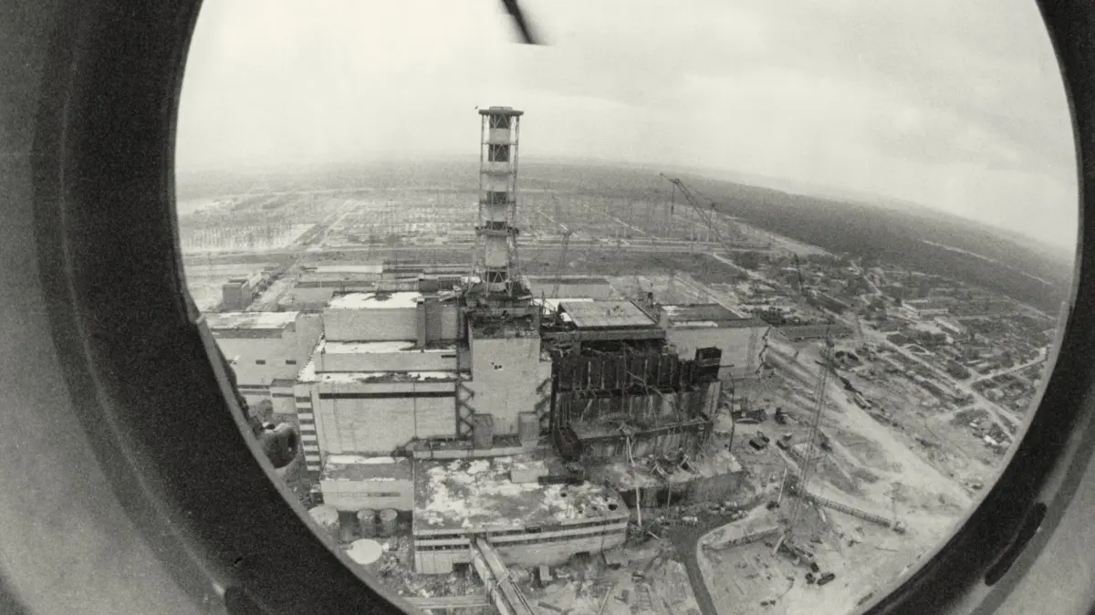 Der Unfall in Tschernobyl und seine Folgen: Der 4. Reaktorblock wurde durch eine Explosion am 26.04.1986 in Tschernobyl voellig zerstoert; Blick auf Block 3 und 4 des Kernkraftwerks waehrend der Reparaturarbeiten (Foto von 1986). Der schwerste Unfall in der Geschichte der zivilen Atomkraftnutzung beginnt in der Nacht - um kurz vor halb zwei Uhr am 26. April 1986. Nach Angaben des Bundesamtes fuer Strahlenschutz und anderer Quellen kommt es im Reaktor Nummer 4 des ukrainischen AKW Tschernobyl waehrend eines planmaessigen Abschaltens und eines gleichzeitigen Versuchsprogramms zur Ueberpruefung verschiedener Sicherheitseigenschaften zu einer atomaren Kettenreaktion. Wie viele Menschen infolge des Unfalls sterben oder erkranken, ist umstritten - die Angaben reichen von einigen Dutzend bis zu mehreren Hunderttausend Betroffenen. Die weitreichenden und langwierigen oekologischen, gesundheitlichen - auch psychischen - und wirtschaftlichen Folgen dieses Unfalls stellen die damalige Sowjetunion und spaeter Russland, Belarus und insbesondere die Ukraine vor grosse Herausforderungen - auch heute noch. (Siehe epd-Stichwort vom 14.04.2026) *** Local Caption *** 00351299