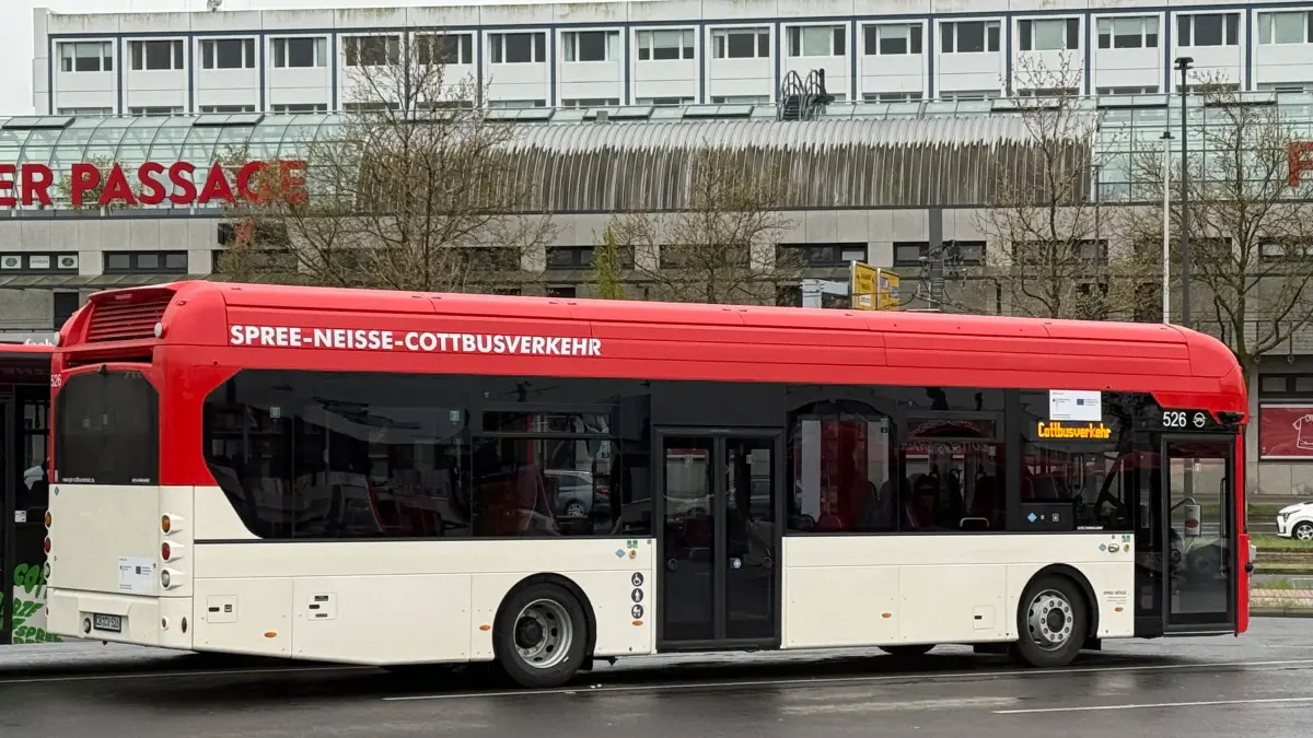 Wasserstoffbus Hauptbahnhof: Ein Wasserstoffbus von Spree-Neiße-Cottbusverkehr steht auf einem Parkplatz am Verkehrsknoten Hauptbahnhof.
Cottbusverkehr bringt die Wasserstoff-Flotte jetzt in Fahrt
In Cottbus und Spree-Neiße starten die ersten vier Wasserstoffbusse in den Linienverkehr. Das ist der Praxistest für die Gefährte und Fahrgäste.
Die ersten Wasserstoffbusse von Cottbusverkehr und Spree-Neiße-Cottbusverkehr gehen am Montag (20. April 2026) in den Linienverkehr. Das bestätigt Unternehmenssprecher Sven Sanders. Vier Fahrzeuge werden im regulären Fahrdienst getestet. Damit endet eine Phase des Stillstands, in der die moderne Technik zwar vorhanden, aber aufgrund fehlender Infrastruktur bislang nicht einsetzbar war.
Dass die Wasserstoffbusse erst jetzt im Stadtbild von Cottbus und im Verkehr über Land auftauchen, hat einen simplen Grund: Es fehlte schlichtweg am nötigen Treibstoff. Die Fahrzeuge standen über einen längeren Zeitraum ungenutzt auf dem Betriebshof, weil die Versorgung vor Ort mit Wasserstoff nicht sichergestellt werden konnte.
Jetzt ist mit der Inbetriebnahme einer mobilen Wasserstofftankstelle auf dem Betriebsgelände von Cottbusverkehr die logistische Hürde aber genommen.