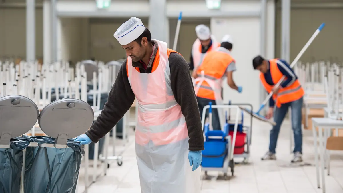 Bilal aus Pakistan sieht am 05.11.2015 in der Kantine in der Landeserstaufnahmeeinrichtung in Ellwangen (Baden-Württemberg) in einen Mülleimer. Der Flüchtling arbeitet in seiner Unterkunft für knapp einen Euro pro Stunde beim Putzdienst. In Baden-Württemberg gibt es mehrere hundert Flüchtlinge, die in ihren Unterkünften arbeiten. Foto: Wolfram Kastl/dpa (zu dpa «Ein-Euro-Jobs bei Asylbewerbern sehr beliebt» vom 05.11.2015) +++(c) dpa - Bildfunk+++