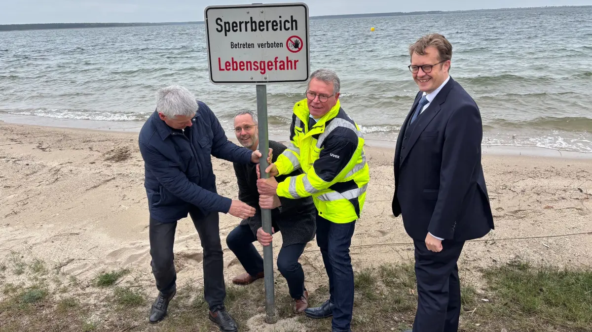 Gemeinsam sind wir stark: Detlev Wurzler vom Zweckverband LSB, der Neu-Seeländer Bürgermeister Marcus Lein, Gerd Richter von der LMBV und Senftenbergs Bürgermeister Andreas Pfeiffer entfernen das letzte Sperrschild vom Liesker Strand am Sedlitzer See.