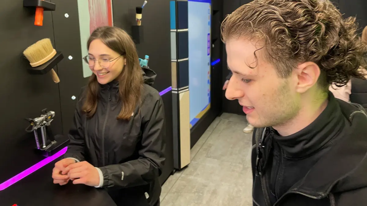 Karolina Grishen lässt sich in Finsterwalde von Pierre Paul Joachim vom Brillux-Show-Truck Techniken erläutern.