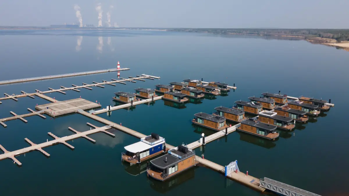 Bärwalder See: ARCHIV - 25.03.2022, Sachsen, Boxberg: Hausboote liegen im Klittener Hafen am Bärwalder See vor dem Kraftwerk Boxberg im Wasser. (Luftaufnahme mit einer Drohne) (zu dpa: «Baden vor der Haustür - Sachsens Seen locken im Sommer») Foto: Sebastian Kahnert/dpa-Zentralbild/dpa +++ dpa-Bildfunk +++