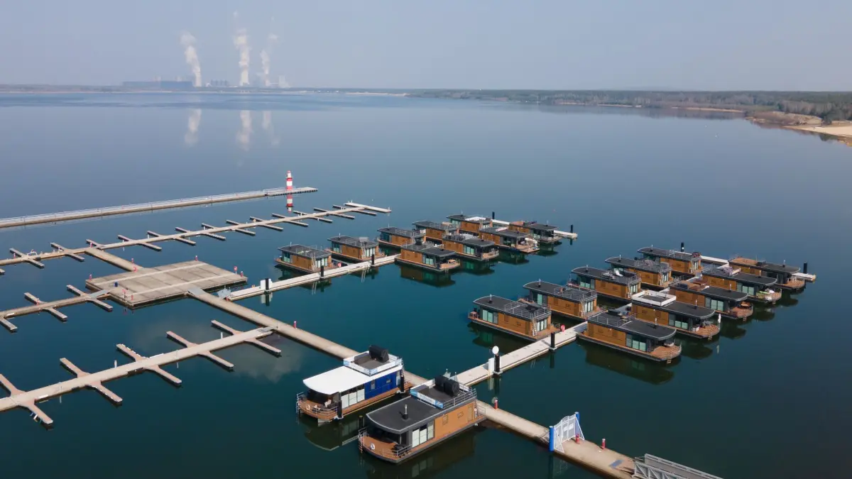 Bärwalder See: ARCHIV - 25.03.2022, Sachsen, Boxberg: Hausboote liegen im Klittener Hafen am Bärwalder See vor dem Kraftwerk Boxberg im Wasser. (Luftaufnahme mit einer Drohne) (zu dpa: «Baden vor der Haustür - Sachsens Seen locken im Sommer») Foto: Sebastian Kahnert/dpa-Zentralbild/dpa +++ dpa-Bildfunk +++
