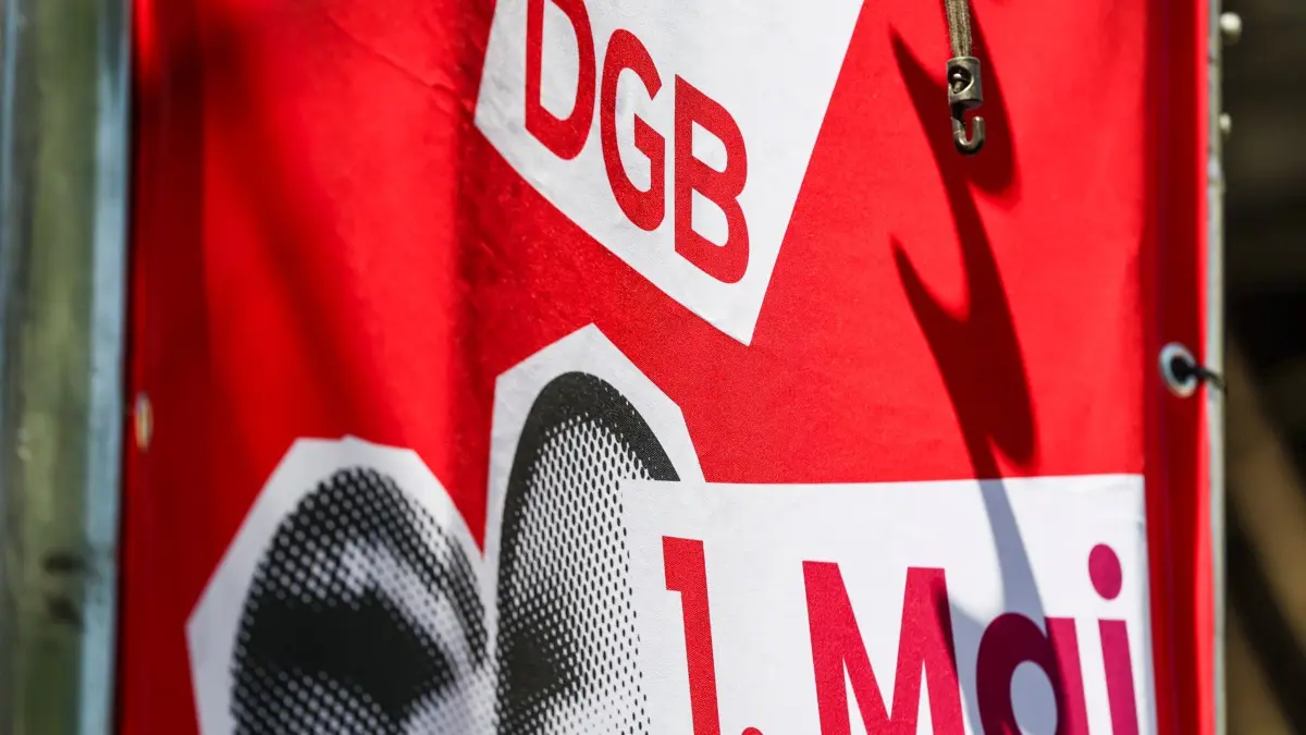 Demonstrationen zum 1. Mai: ARCHIV - 01.05.2025, Nordrhein-Westfalen, Siegburg: Eine Fahne vom DGB zum 1. Mai hängt an der Bühne. Bei landesweit 76 Veranstaltungen mit vielen prominenten Rednern wollen die Gewerkschaften in Nordrhein-Westfalen am 1. Mai ihre Forderungen für gute Arbeitsbedingungen und mehr Verteilungsgerechtigkeit untermauern. Zu den Kundgebungen, Festen und Empfängen am «Tag der Arbeit» erwartet der Deutsche Gewerkschaftsbund Zehntausende Teilnehmer. (zu dpa: «Bas, Klingbeil und Wüst zu DGB-Kundgebungen erwartet») Foto: Christoph Reichwein/dpa +++ dpa-Bildfunk +++