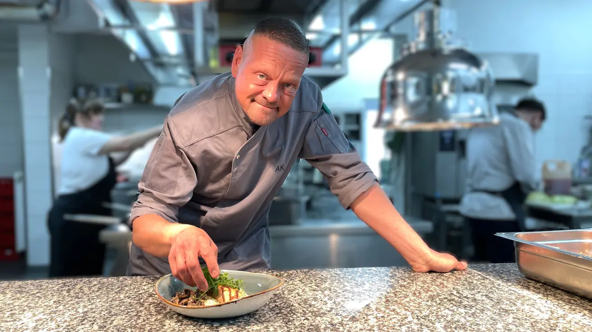 Der Küchenchef im Hotel Seeschlösschen in Senftenberg, Alexander Koppe, posiert am 24.04.2026 mit einem Essen für Tagungsgäste in der Küche.