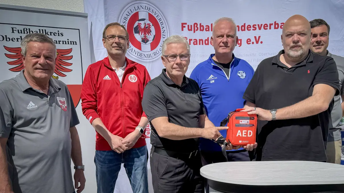 Fußballkreis-Chef Oberhavel/Barnim Michael Reichert, FLB-Projektleiter Ronny Beyer, FLB-Präsident Jens Kaden, Alexander Wollanik vom FSVBernau, Dietmar Engelhard (Geschäftsführer der BSS HuB) und Paul Olschewski vom Fußballkreis Oberhavel/Barnim bei der Übergabe eines AED-Geräts beim FSV Bernau.