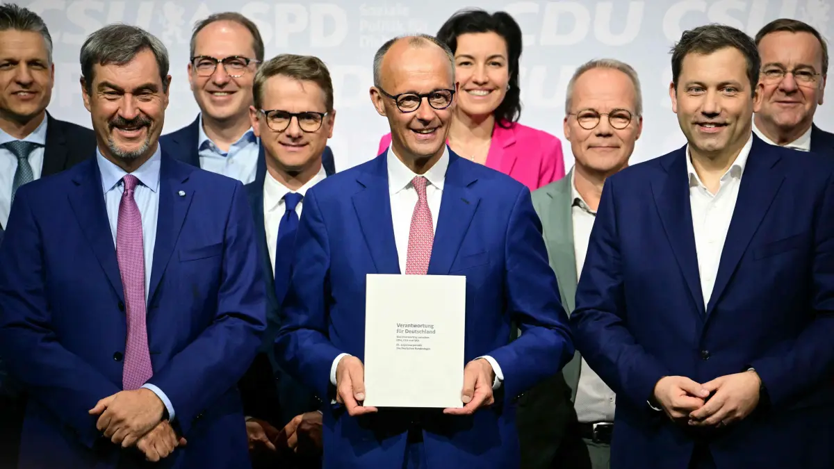 (FILES) The leader of Germany's conservative Christian Democratic Union (CDU) party Friedrich Merz (C), the co-chairman of Germany's Social Democratic Party (SPD) Lars Klingbeil (C-R) and the leader of Bavaria's conservative Christian Social Union (CSU) party Markus Soeder (C-L) pose with members of the new cabinet and party officials after signing a coalition deal to form the country's new government, on May 5, 2025 in Berlin. A year ago, German lawmakers elected conservative Friedrich Merz as chancellor. The chancellor had vowed to diminish the appeal of the country's far-right AfD party with two main strategies -- taking a tough stance on immigration to outflank the far-right party on the issue, and aiming to enact bold reforms to prove that centrist parties are still capable of acting. Tighter immigration rules have led to a significant decrease in arrivals -- but the chancellor does not appear to be benefitting political. Meanwhile the reform drive has stalled due to bickering between the conservative CDU and the social democratic SPD coalition parties, with the long-struggling economy making a slower than expected recovery. (Photo by Tobias SCHWARZ / AFP)