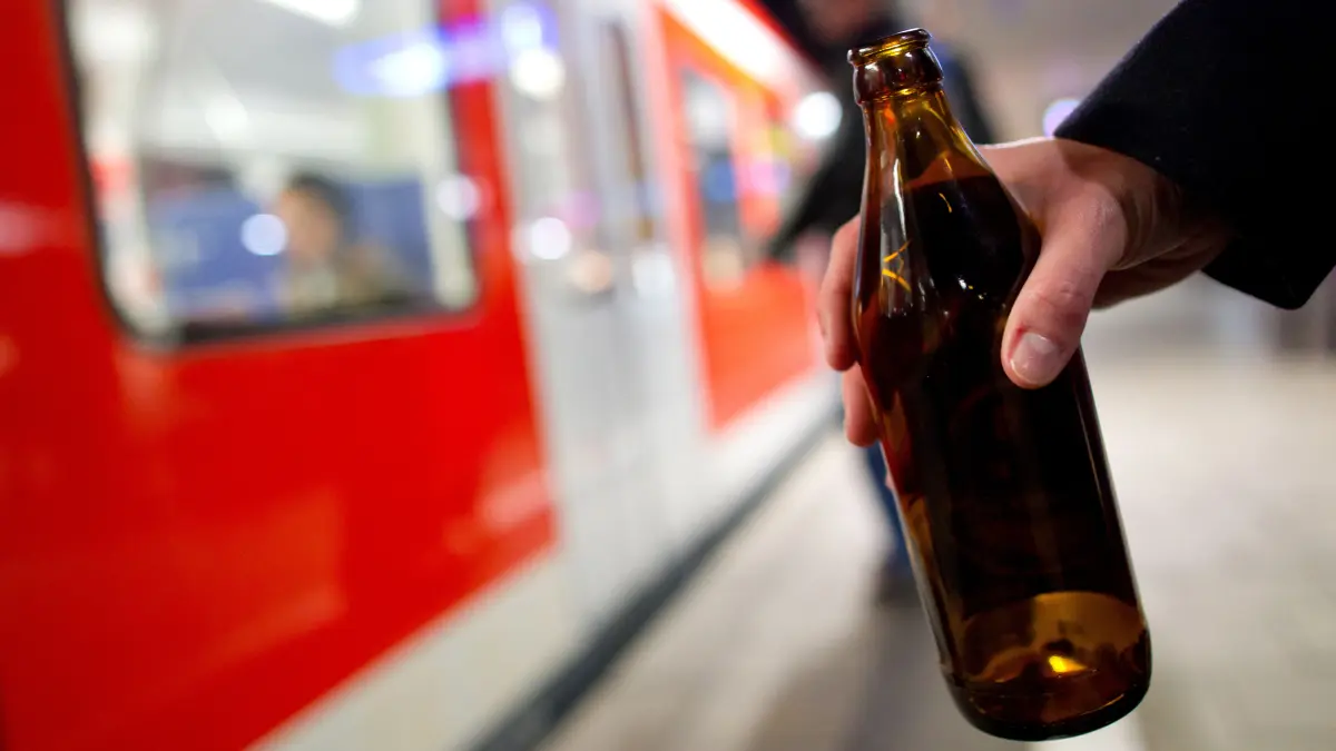 Eine Person hält auf einem Bahnsteig eine Bierflasche in der Hand. Seit dem 1. Mai gibt es in Berlin zwei Bahnhöfe an denen der Konsum von Alkohol verboten ist. Infrastrukturminister Robert Crumbach wünscht sich eine Debatte über ein generelles Alkoholverbot in Brandenburg. (Symbolbild)