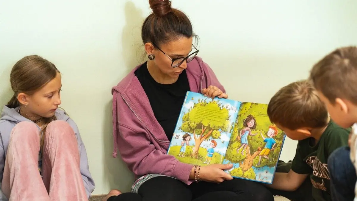 Melanie Gade von der Schulleitung der Freien Alternativschule Lausitz in Drebkau (Spree-Neiße) schaut sich gemeinsam mit den Kindern ein Buch an.